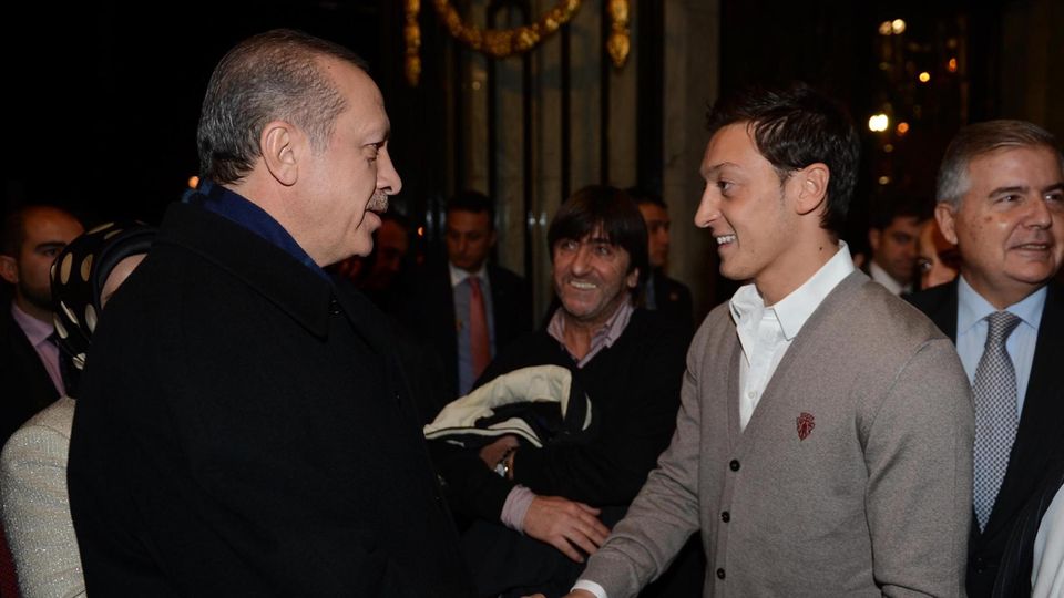 Erdogan und Mesut Özil stehen sich gegenüber, schütteln sich die Hand und lächeln