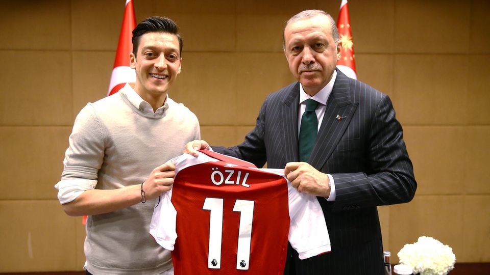 Links steht Mesut Özil, rechts Erdogan. Gemeinsam halten sie ein rotes Arsenal-Trikot mit "Özil" und der 11 auf dem Rücken