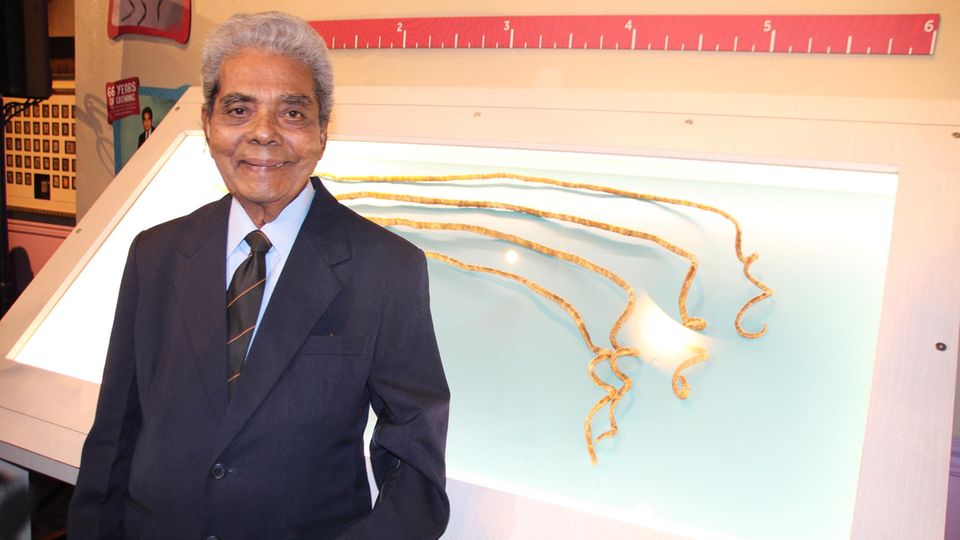 Der Inder Shridhar Chillal und seine Fingernägel Shridhar Chillal neben seinen in einer Vitrine ausgestellten Fingernägeln