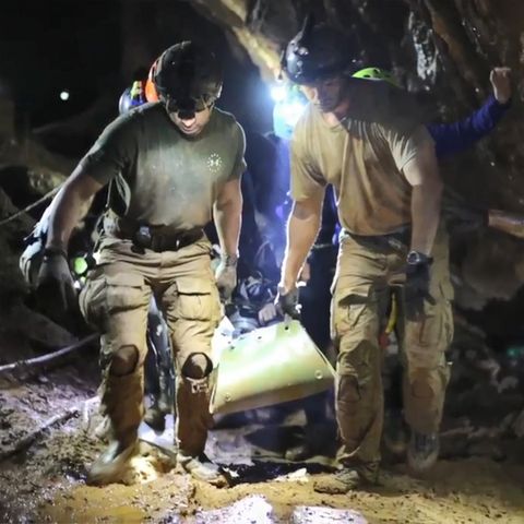 Helfer tragen einen Jungen, der auf einer Liege liegt, aus der Tham-Luang-Höhle
