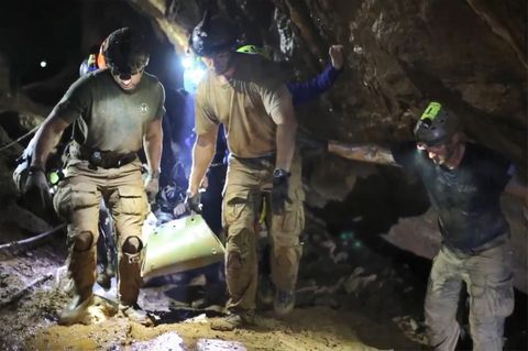 Helfer tragen einen Jungen, der auf einer Liege liegt, aus der Tham-Luang-Höhle