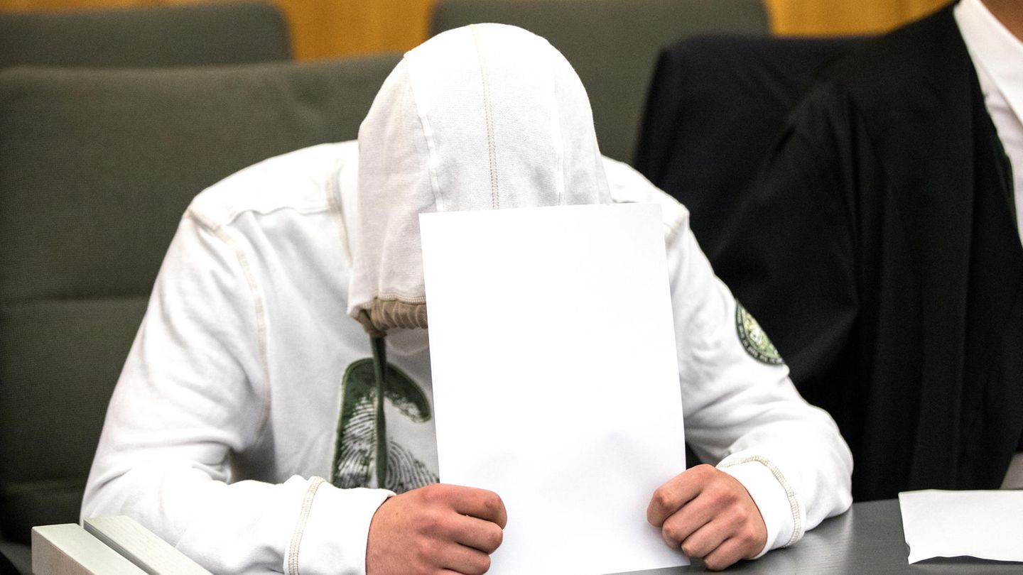 Ein Angeklagter vermummt sich vor den Fotografen. Er ist wegen Vergewaltigung angeklagt