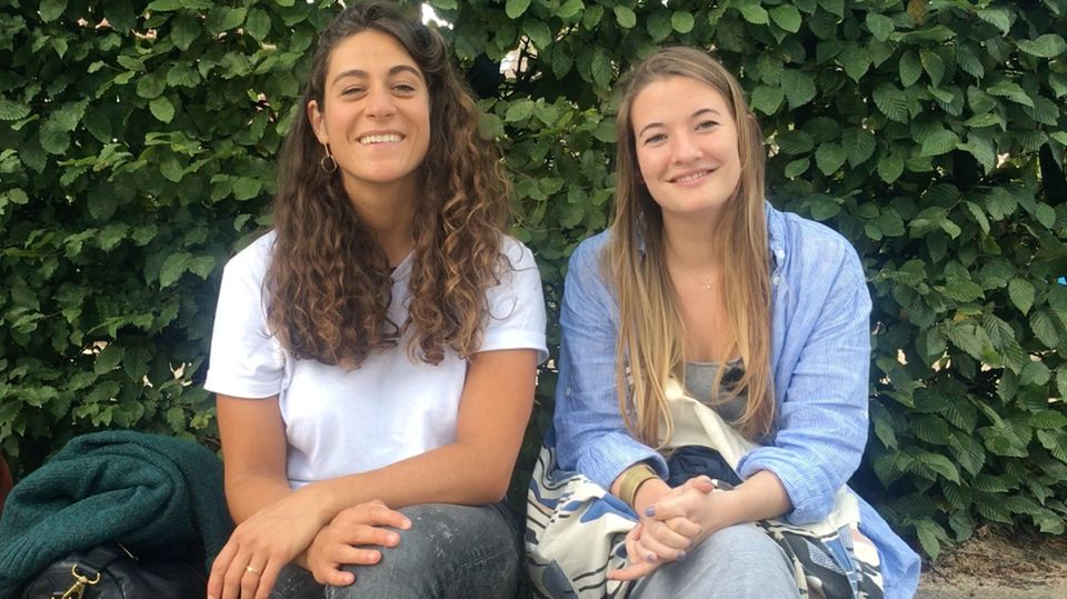 Two smiling girls are sitting on a bench
