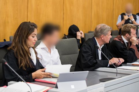 Die Angeklagten (2.v.l, 3.v.l) sitzen im Gerichtssaal neben ihren Anwälten