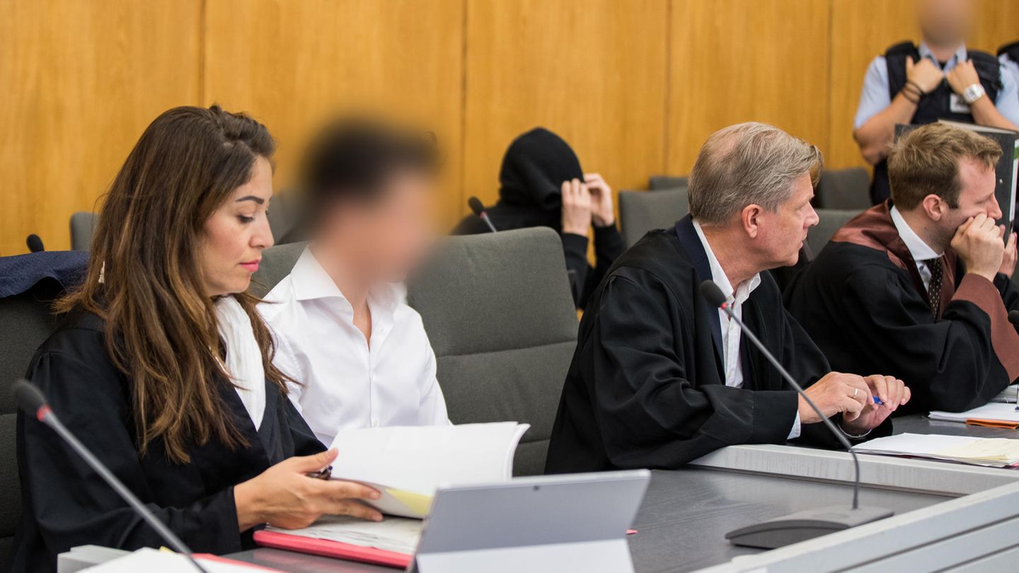 Die Angeklagten (2.v.l, 3.v.l) sitzen im Gerichtssaal neben ihren Anwälten