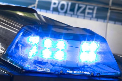Auf dem Dach eines Polizeiautos blinkt ein Blaulicht, im Hintergrund steht "Polizei" auf einem anderen Auto