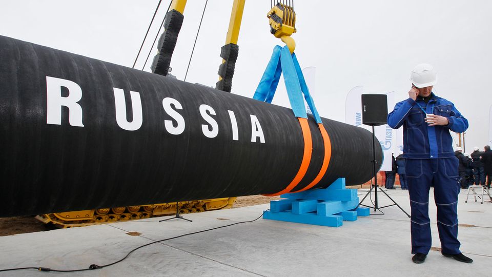 Ein russischer Bauarbeiter telefoniert neben einem Rohrstück für die Gas-Pipeline Nord Stream