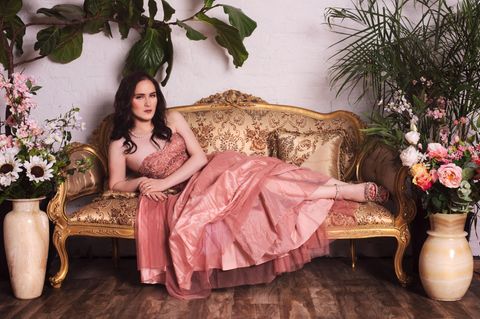 Abby Stein liegt in einem rosa Kleid auf einem Sofa.