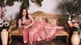 Abby Stein liegt in einem rosa Kleid auf einem Sofa.