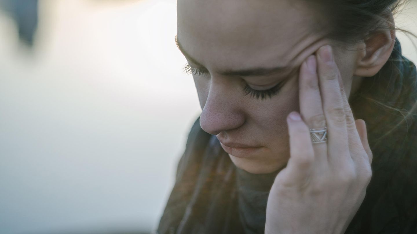 Eine junge Frau fasst sich an den Kopf