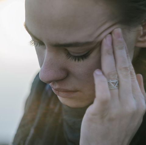 Eine junge Frau fasst sich an den Kopf