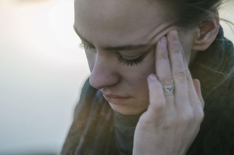 Eine junge Frau fasst sich an den Kopf