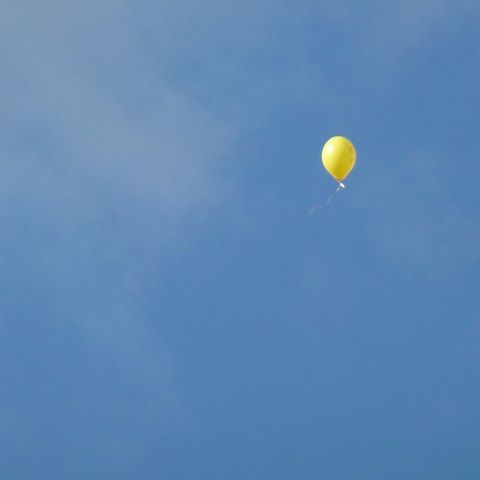 Ein gelber Luftballon schwebt in den Himmel