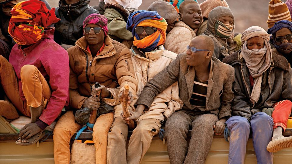 Niger: Holzstöcke, festgebunden an der Ladefläche, sind der einzige Schutz der Männer gegen einen Sturz vom Lastwagen auf der Reise durch die Sahara Holzstöcke, festgebunden an der Ladefläche, sind der einzige Schutz der Männer gegen einen Sturz vom Lastwagen auf der Reise durch die Sahara