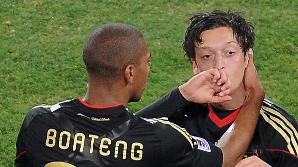 Mesut Özil steht im schwarzen DFB-trikot auf dem Platz und jubelt, Jérôme Boateng beglückwünscht ihn