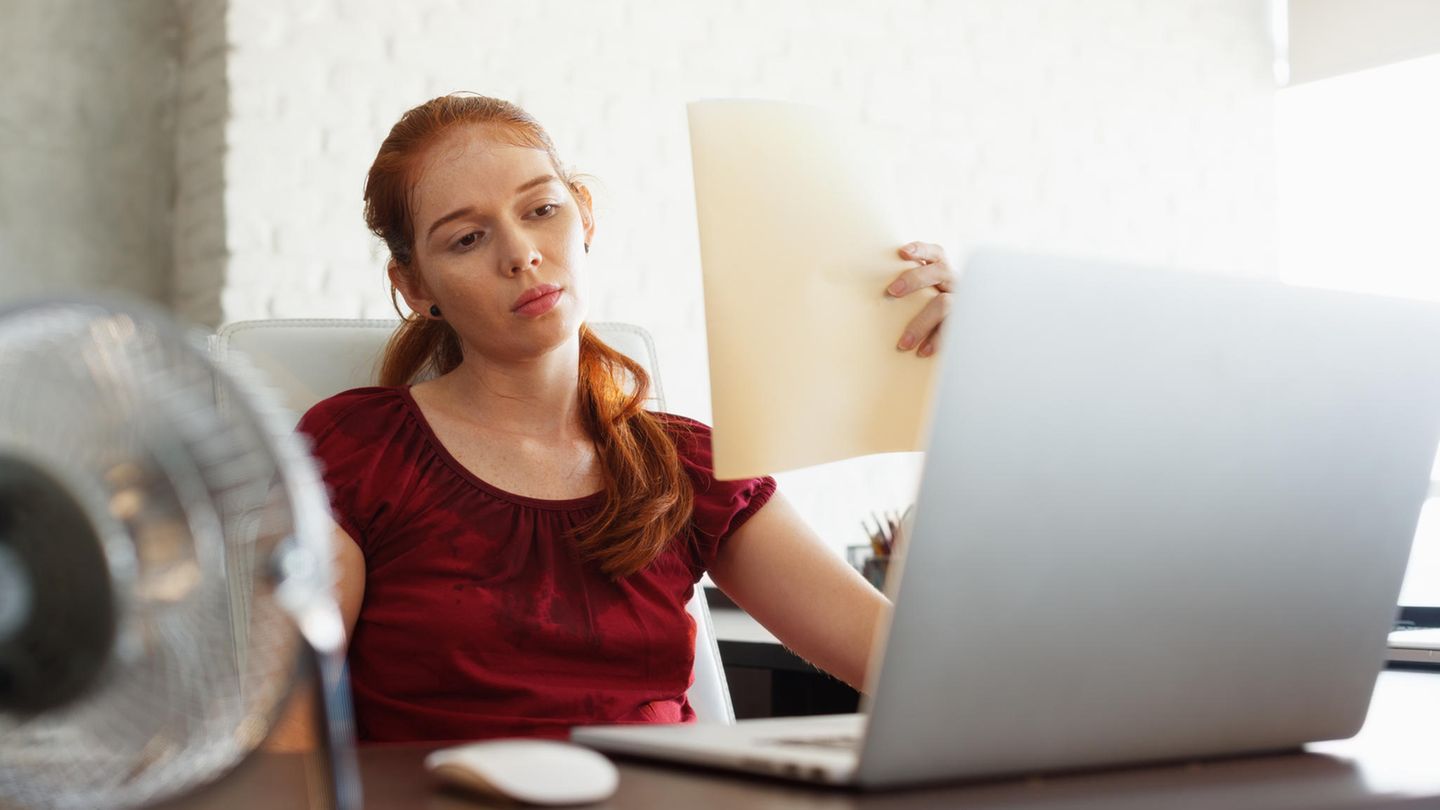 Eine Frau sitzt im Büro und schwitzt