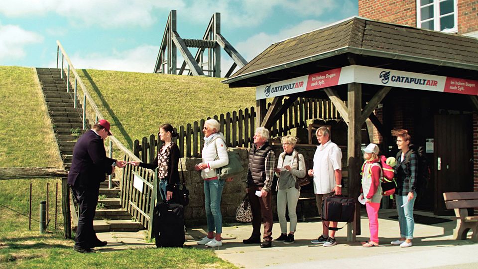 Gate am Deich: Szene aus dem Clip "Catapult Air - Im hohen Bogen nach Sylt", der auf humorvolle Weise den zweigleisigen Ausbau der Bahnstrecke nach Westland fordert.