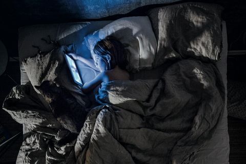 Ein Junge schaut Cartoons im Bett