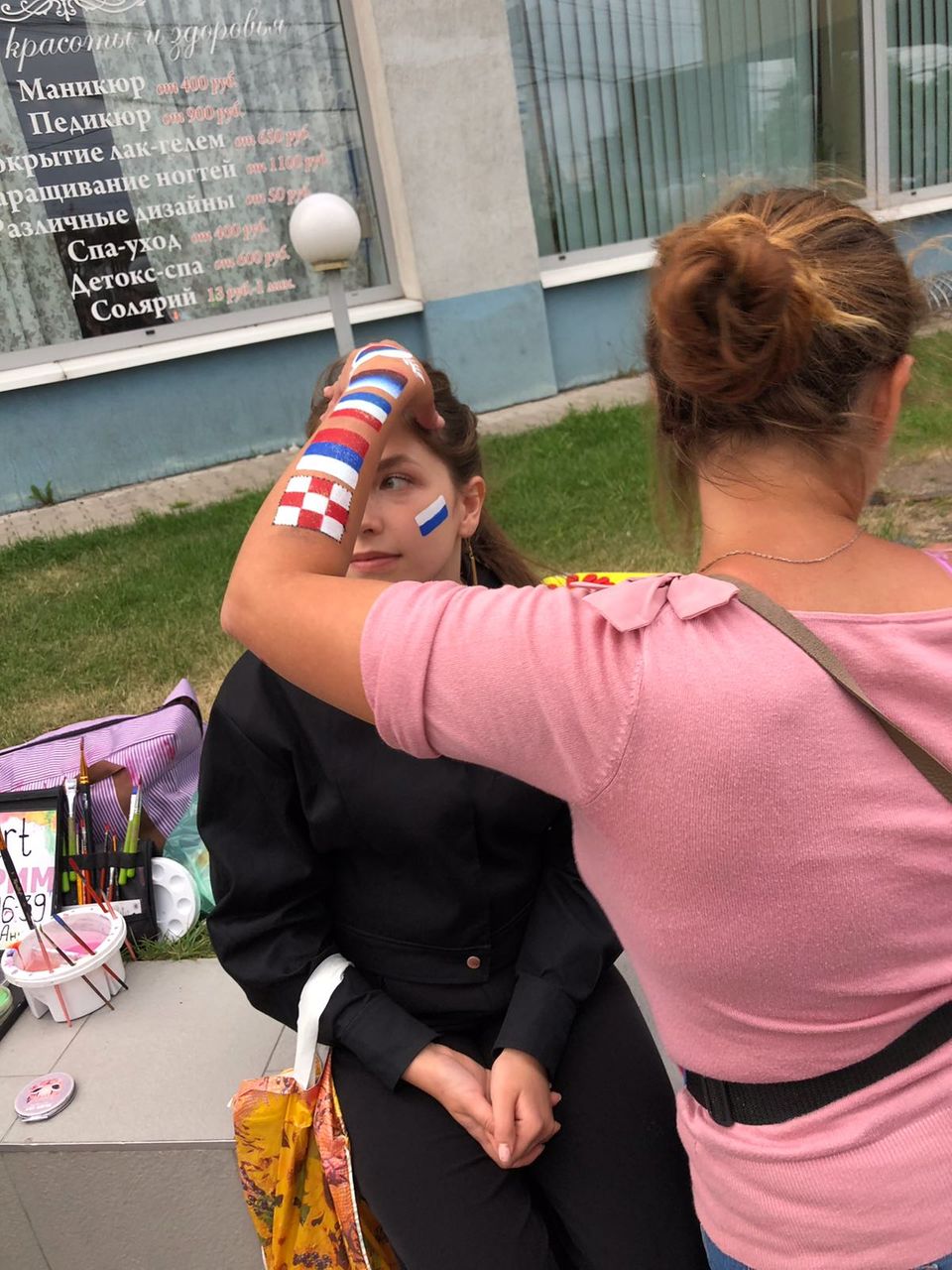 Flaggen schminken Eine junge Frau bekommt die russische Flagge auf die Wange gemalt