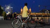 Der Vollmond taucht über der Oberbaumbrücke über der Spree auf, während Berliner sich am Spreeufer ein Feuerwerk anschauen