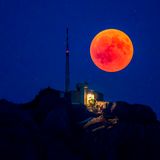 Ein Foto aus der Schweiz: Rot steigt der Vollmond im Kanton Appenzell hinter dem Berg Säntis auf 2502 Metern Höhe im Alpstein auf.