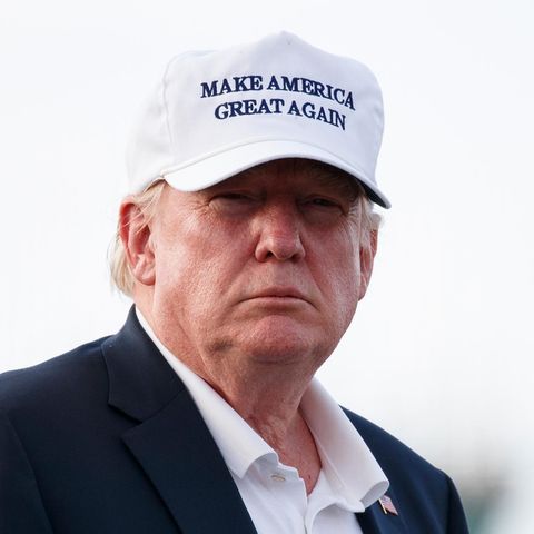 US-Präsident Donald trump steht im Freien und trägt zu Jackett und offenem Hemd ein weißes Cap mit "Make America great again"