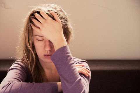Eine junge Frau fasst sich an den Kopf