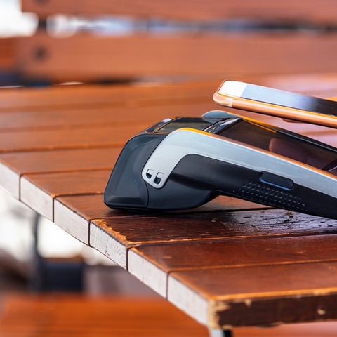 Ein iPhone mit Apple Pay zahlt in einem Restaurant-Terminal