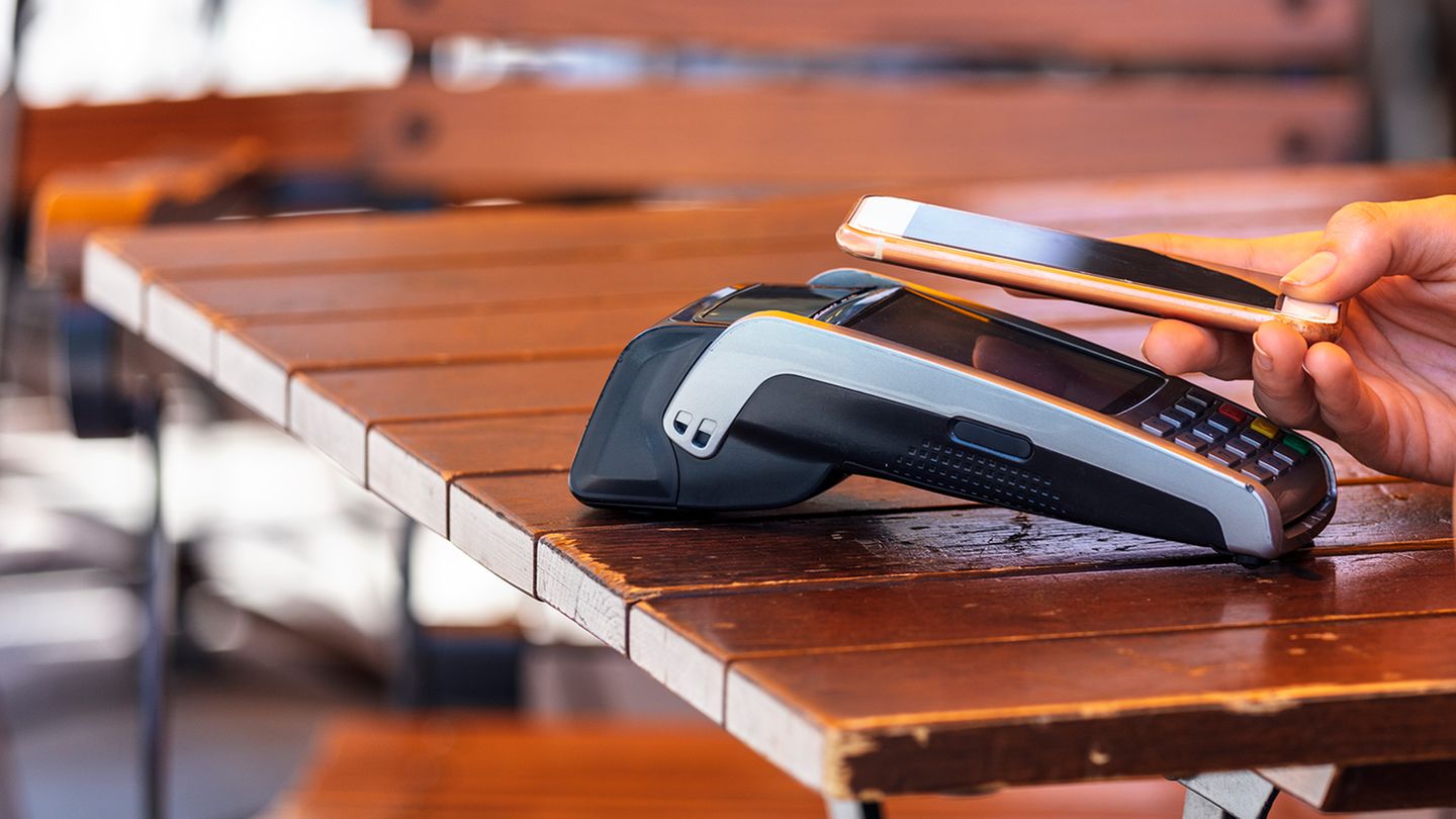 Ein iPhone mit Apple Pay zahlt in einem Restaurant-Terminal