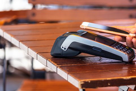 Ein iPhone mit Apple Pay zahlt in einem Restaurant-Terminal