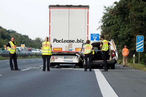 Ein beschädigter Kleintransporter steht nach einem Auffahrunfall hinter einem Lkw auf der Autobahn A2