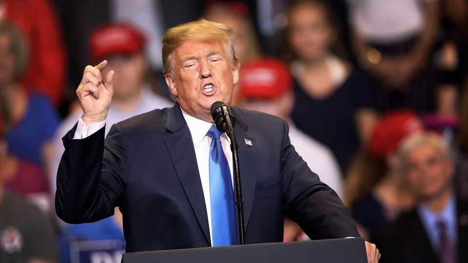 Donald Trump Donald Trump steht an einem Redepult mit dem Wappen des US-Präsidenten und gestikuliert mit seiner rechten Hand