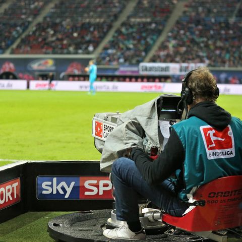 Ein Kameramann filmt die Bundesliga. Auf der Bande um ihn herum steht "Sky Sport".