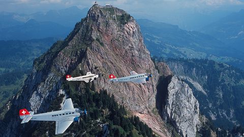 Drei Flugzeuge vom Typ Junkers JU 52 im Formationsflug über den Bergen.