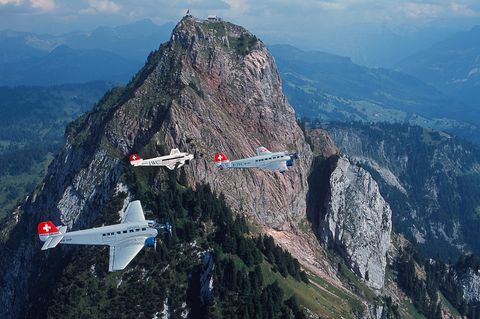 Drei Flugzeuge vom Typ Junkers JU 52 im Formationsflug über den Bergen.