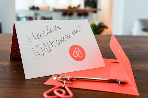 Ein Schlüssel mit einem Airbnb-Anhäger und eine Herzlich-Willkommen-Karte liegen in der Wohnung eines  Gastgebers.