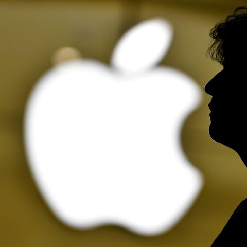 Ein Mann steht vor dem Logo von Apple
