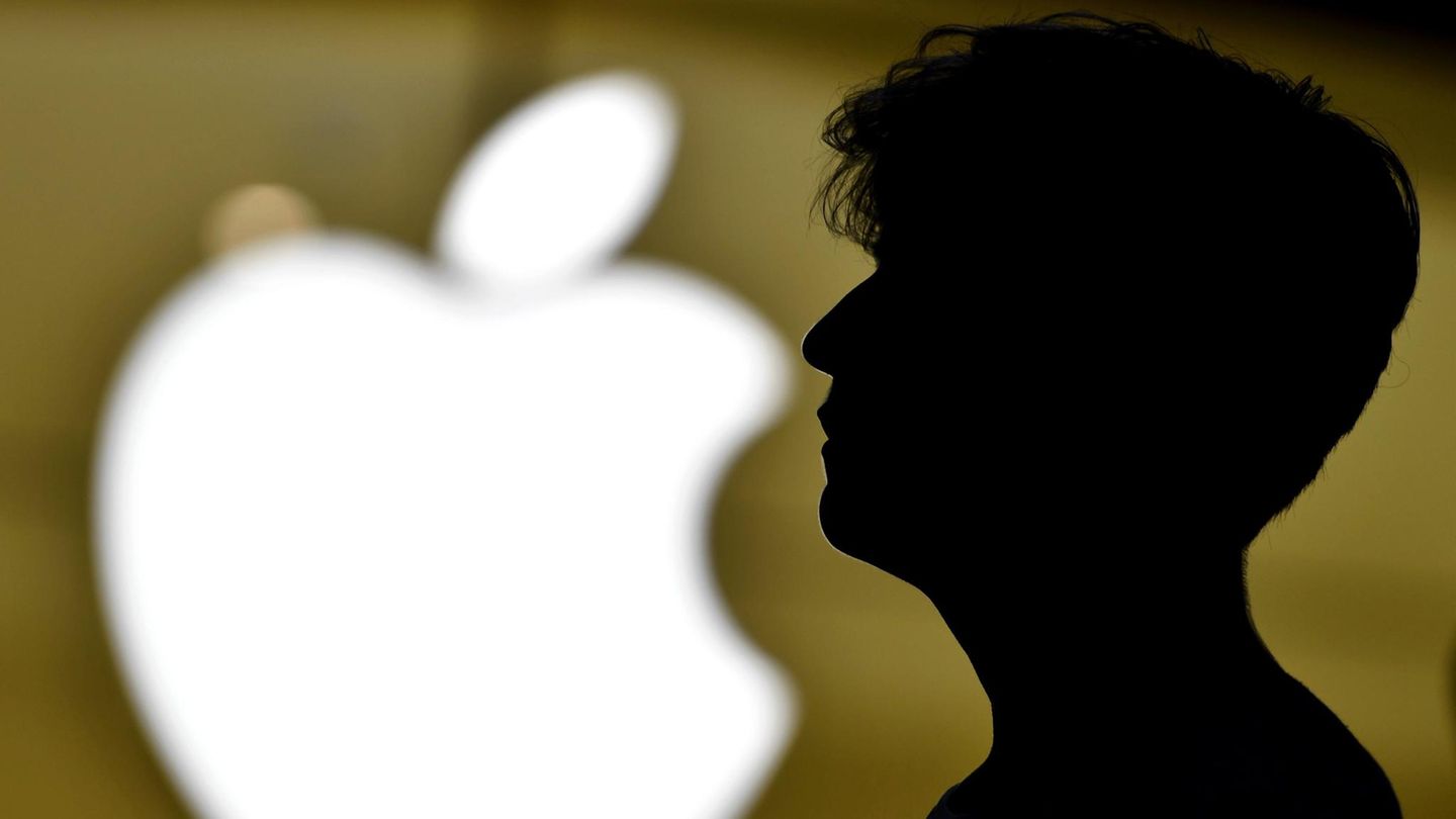 Ein Mann steht vor dem Logo von Apple
