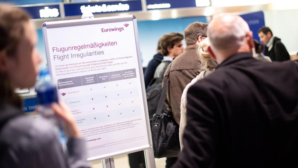 Reisende warten am Flughafen vor einem Schalter von Eurowings auf Umbuchungsmöglichkeiten.