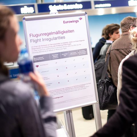 Reisende warten am Flughafen vor einem Schalter von Eurowings auf Umbuchungsmöglichkeiten.