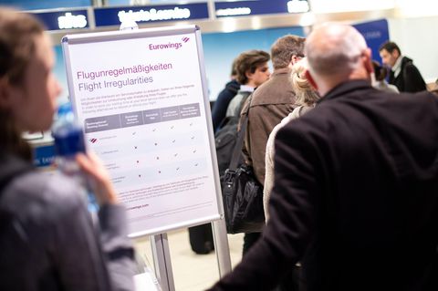 Reisende warten am Flughafen vor einem Schalter von Eurowings auf Umbuchungsmöglichkeiten.