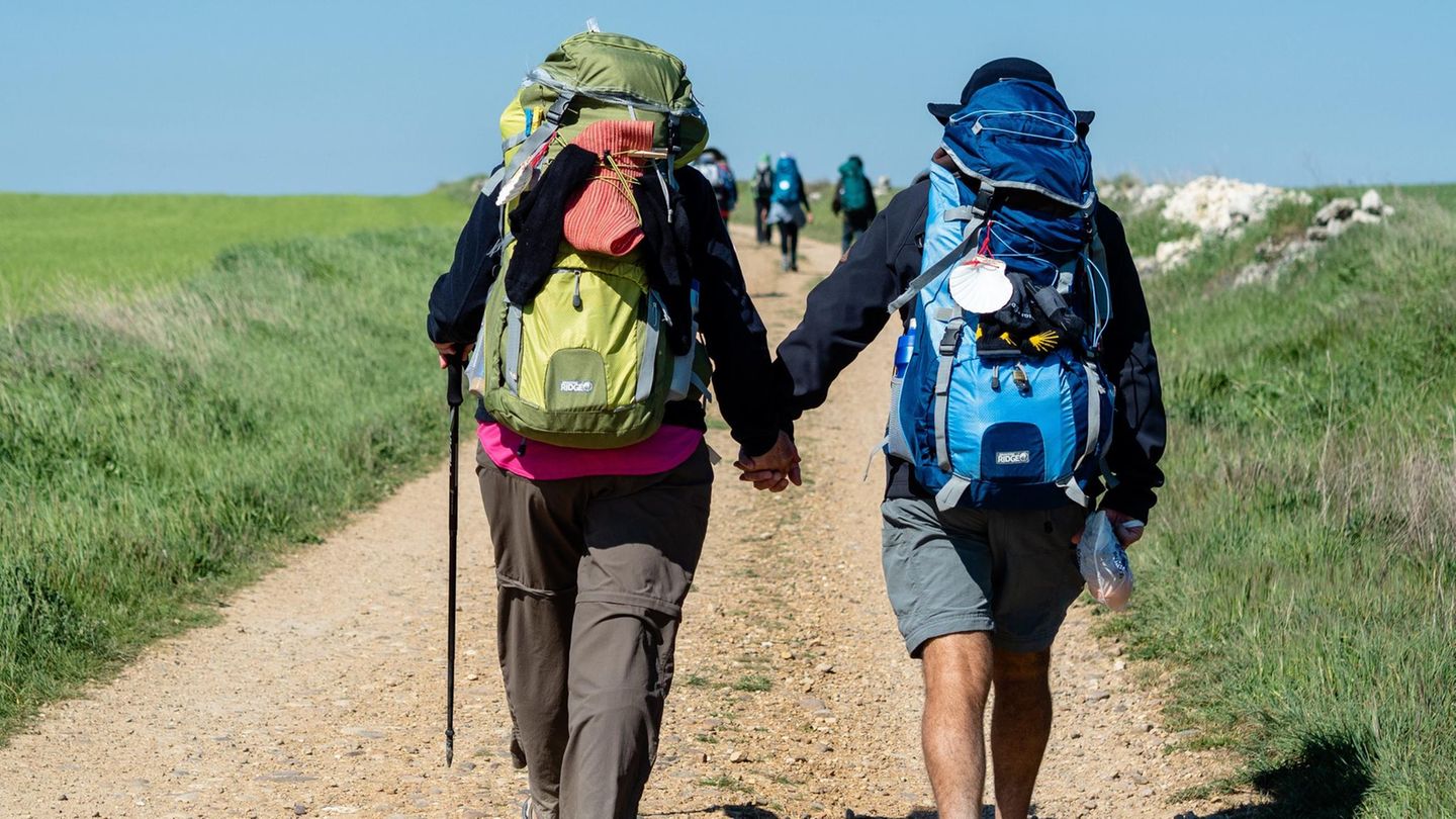 Zwei Pilger gehen Hand in Hand auf dem Jakobsweg Santiago de Compostela entgegen.
