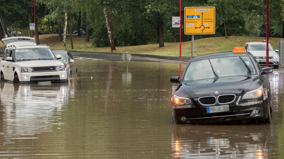 Im hessischen Stadtallendorf stehen Pkw auf einer nach einem kurzen und starken Regenguss überfluteten Straße. Die Regenmassen hatten ganze Straßenzüge überflutetet, Gebäude standen im Keller ebenfalls unter Wasser