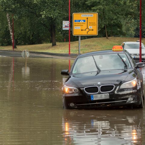 Im hessischen Stadtallendorf stehen Pkw auf einer nach einem kurzen und starken Regenguss überfluteten Straße. Die Regenmassen hatten ganze Straßenzüge überflutetet, Gebäude standen im Keller ebenfalls unter Wasser