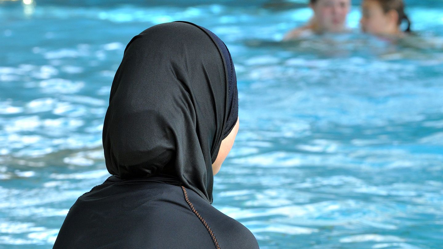 Burkini oder Burka – Frau schaut im Schwimmbad aufs Becken