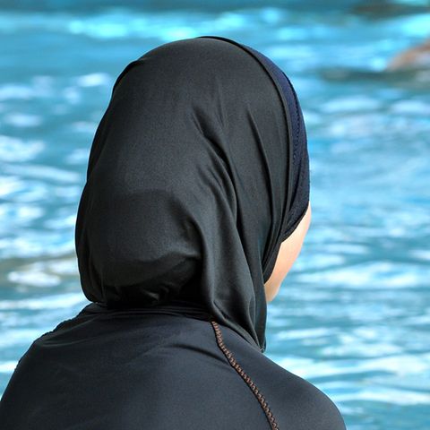 Burkini oder Burka – Frau schaut im Schwimmbad aufs Becken