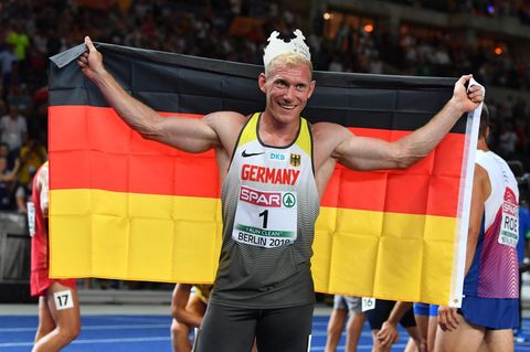 Zehnkämpfer Arthur Abele jubelt mit einer Pappkrone auf dem Kopf und einer Deutschland-Flagge in den ausgebreiteten Armen