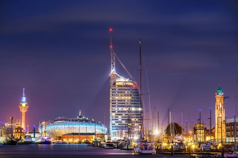 Das neue Bremerhaven bei Nacht: das Klimahaus 8 Grad Ost in Bildmitte und das hohe Hotel Atlantic Sail City rechts daneben.