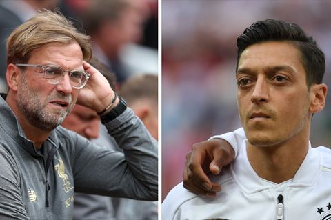 Links sitzt Jürgen Klopp auf einer Trainerbank und streicht sich mit links durchs Haar. Rechts steht Mesut Özil bei der Hymne
