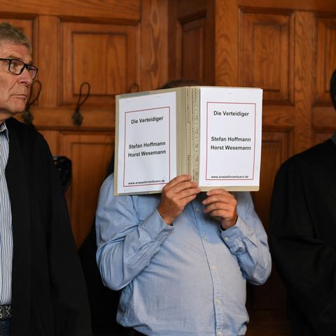 Bremen: Der wegen Mordes Angeklagte hält einen Schnellhefter vor sein Gesicht